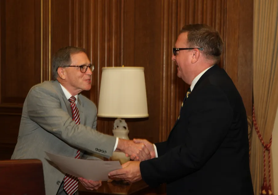 Two men in suits shaking hands indoors formally