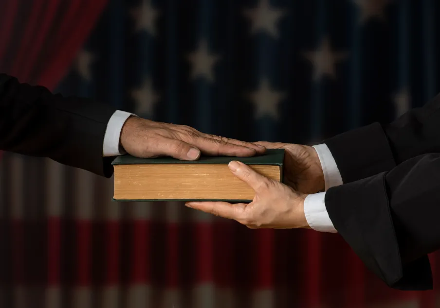 Person swearing oath on book with American flag background