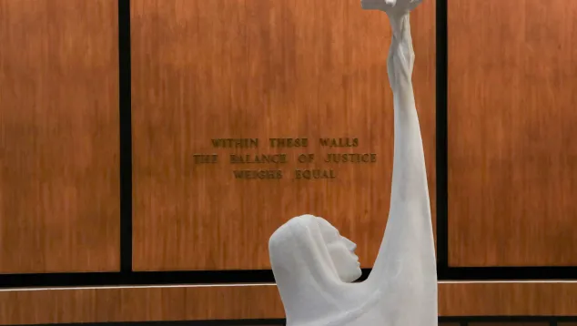 Interior courthouse photo of wall that reads "within these walls the balance of justice weighs equal."